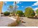 Landscaped backyard featuring mature trees, decorative rock, and a round fountain element at 10634 E Cedar Waxwing Dr, Sun Lakes, AZ 85248
