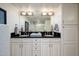 Bright bathroom featuring double sinks, framed mirror, black counters, and white cabinets at 12212 N Paradise Village S Pkwy # 444, Phoenix, AZ 85032