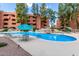 Beautiful community pool area with tables, chairs, lounge seating, and shade umbrellas surrounded by mature trees and desert landscaping at 12212 N Paradise Village S Pkwy # 444, Phoenix, AZ 85032
