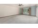 Bright living room with neutral carpet, ceiling fan, large window, and sliding glass door to outdoor patio at 12939 W Prospect Dr, Sun City West, AZ 85375