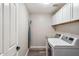 Functional laundry room with a modern washer and dryer set, overhead cabinets, and an ironing board at 16044 N 106Th Way, Scottsdale, AZ 85255