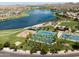 Aerial view of a lakefront park with tennis courts, volleyball courts, basketball court, and picnic areas surrounded by palm trees at 18346 W Sweet Acacia Dr, Goodyear, AZ 85338