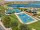 Aerial view of well-maintained blue basketball and tennis courts, set in a park with green spaces and palm trees at 18346 W Sweet Acacia Dr, Goodyear, AZ 85338