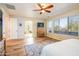 The bright bedroom with laminate wood floors features a ceiling fan and a view to the ensuite bathroom at 18346 W Sweet Acacia Dr, Goodyear, AZ 85338