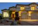 Charming desert home exterior showcasing manicured landscaping and a three car garage at twilight at 18346 W Sweet Acacia Dr, Goodyear, AZ 85338