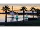 Serene lake view at dusk with illuminated fountains and palm trees, creating a tranquil ambiance at 18346 W Sweet Acacia Dr, Goodyear, AZ 85338