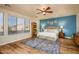 Serene main bedroom with a blue accent wall, a ceiling fan, and wood-style flooring at 18346 W Sweet Acacia Dr, Goodyear, AZ 85338