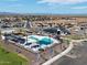 Community aerial view showcasing a large pool, splashpad, playground, and surrounding homes against a mountain backdrop at 3513 E Audrey Dr, San Tan Valley, AZ 85143