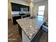 Modern kitchen featuring a large island with a sink, granite counters, and black cabinets at 36992 W Capri Ave, Maricopa, AZ 85138
