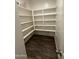 Walk-in pantry with ample shelving and dark laminate flooring for organized storage at 36992 W Capri Ave, Maricopa, AZ 85138