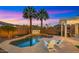 Inviting backyard pool area featuring lush palm trees and a tranquil water feature under a vibrant sunset sky at 3953 E Lafayette Ave, Gilbert, AZ 85298