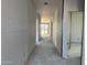 Interior shot of an unfinished hallway with visible drywall, leading to a bright, open space at 5631 W Summerside Rd, Laveen, AZ 85339