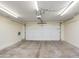 Spacious garage with concrete flooring, and a white garage door, lit with fluorescent lights overhead at 6439 W Adobe Dr, Glendale, AZ 85308