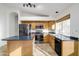 Well-lit kitchen featuring stainless steel appliances, wooden cabinets, and an island with a dark countertop at 6439 W Adobe Dr, Glendale, AZ 85308