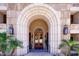 Arched entrance with stone accents, double doors, and palm trees creating a luxurious curb appeal at 7181 E Camelback Rd # 208, Scottsdale, AZ 85251