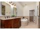 Bathroom with double vanity, soaking tub, and tile surround at 7955 E Chaparral Rd # 120, Scottsdale, AZ 85250