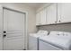 Laundry room featuring front-load washer and dryer, storage cabinets, and a door at 7955 E Chaparral Rd # 120, Scottsdale, AZ 85250