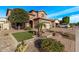 Well-maintained front yard featuring a paver driveway, artificial grass, mature trees, and easy access to the street at 10746 W Desert Elm Ln, Peoria, AZ 85383