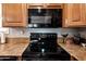 A close-up of black appliances and granite countertops, with matching brown cabinets above at 11596 W Sierra Dawn Blvd # 293, Surprise, AZ 85378