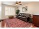 Inviting living room featuring a leather couch, decorative rug, and plantation shutters at 16292 N Naegel Dr, Surprise, AZ 85374