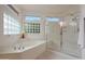 Bright bathroom features a soaking tub with glass block window, a glass-enclosed shower and white cabinets at 20416 N Palm Canyon Dr, Surprise, AZ 85374