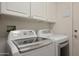 Laundry room features front loading washer and dryer with white cabinets above at 20416 N Palm Canyon Dr, Surprise, AZ 85374