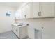 Well-appointed laundry room features cabinetry, sink, and stylish tile flooring at 21422 W Meadowbrook Ave, Buckeye, AZ 85396