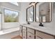 Bathroom featuring a double vanity, framed mirrors, a soaking tub, and a large window at 2411 W Oberlin Way, Phoenix, AZ 85085