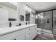 Bright bathroom features double sinks, white cabinets, black hardware, and a glass enclosed shower at 1027 W Natal Ave, Mesa, AZ 85210