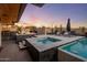 Expansive backyard features a sparkling pool, hot tub, fire pit, outdoor kitchen, and lush desert landscaping at 10381 E Loving Tree Ln, Scottsdale, AZ 85262