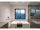 Modern bathroom features a sleek tub under a window and a stylish tiled shower at 10381 E Loving Tree Ln, Scottsdale, AZ 85262