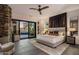 Modern bedroom featuring a stone accent wall, plush bed and expansive patio at 10381 E Loving Tree Ln, Scottsdale, AZ 85262