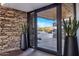 Modern entryway with stone walls and views of the landscaped front yard through glass doors at 10381 E Loving Tree Ln, Scottsdale, AZ 85262