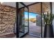 Modern entryway with stone walls and views of the landscaped front yard through glass doors at 10381 E Loving Tree Ln, Scottsdale, AZ 85262