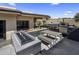 Modern outdoor kitchen featuring a built-in grill, pizza oven, fire pit, desert landscaping, and dining area at 10381 E Loving Tree Ln, Scottsdale, AZ 85262