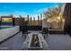 Outdoor patio area featuring a modern glass-enclosed fire pit and lounge chairs with desert landscaping and outdoor television at 10381 E Loving Tree Ln, Scottsdale, AZ 85262