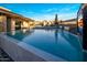 A backyard pool view with outdoor kitchen, pool with textured wall, waterfall features, and lounge chairs at 10381 E Loving Tree Ln, Scottsdale, AZ 85262