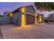 Well-lit home featuring a brick driveway, desert landscaping, and warm exterior lighting at twilight at 10822 E Ramblewood Cir, Mesa, AZ 85212