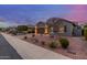 Charming single-story home with well-manicured landscaping and warm exterior lighting at twilight at 10822 E Ramblewood Cir, Mesa, AZ 85212