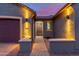 A beautifully lit home entrance with an arched doorway, concrete benches, and desert landscaping at 10822 E Ramblewood Cir, Mesa, AZ 85212