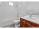 Bright bathroom features a tub with white tile surround, wood vanity and a white countertop sink at 13587 W Cypress St, Goodyear, AZ 85395