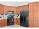 Well-lit kitchen features wood cabinets and black appliances, offering both style and functionality at 13587 W Cypress St, Goodyear, AZ 85395