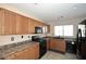 Kitchen with wooden cabinets, black appliances, and ample counter space at 21047 N Alma Dr, Maricopa, AZ 85138