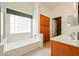 Bathroom featuring tub, dual sinks, wood cabinets, and natural light from the window at 28604 N 21St Ln, Phoenix, AZ 85085