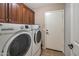 Laundry room with a washer, dryer, wood cabinets, and access to an exterior door at 35282 N Shorthorn Trl, San Tan Valley, AZ 85143