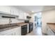 Well-lit kitchen with black appliances, white cabinetry, and wood-look tile flooring at 3914 E Surrey Ave, Phoenix, AZ 85032