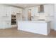 Bright kitchen boasts white cabinetry, stainless steel appliances, a spacious island and wood look tile flooring at 40113 N Alameda Dr, San Tan Valley, AZ 85140