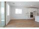 Bright living room with white walls, wood look tile floors, and windows offering natural light and kitchen view at 40113 N Alameda Dr, San Tan Valley, AZ 85140