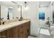 Well-lit bathroom boasts a dual sink vanity, sleek black fixtures, and a glimpse into a separate tub and shower area at 4625 E Mountain View Rd, Phoenix, AZ 85028