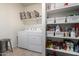 Laundry room with washer, dryer, and organized shelving unit in a neutral color palette at 5101 E Sharbel Rd, San Tan Valley, AZ 85143